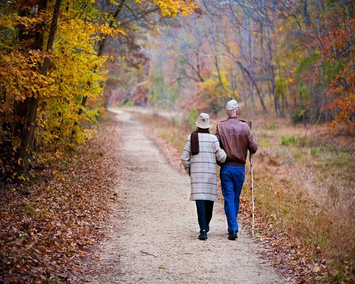 Active walking older couple outside in park